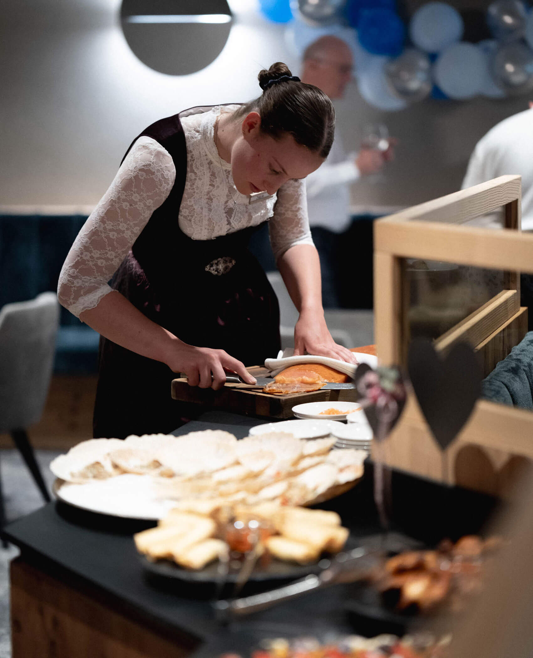 Eine Frau schneidet Lachs an einem Büffettisch mit Tellern voller Speisen bei einer Veranstaltung im Haus. - Hotel Magdalenahof