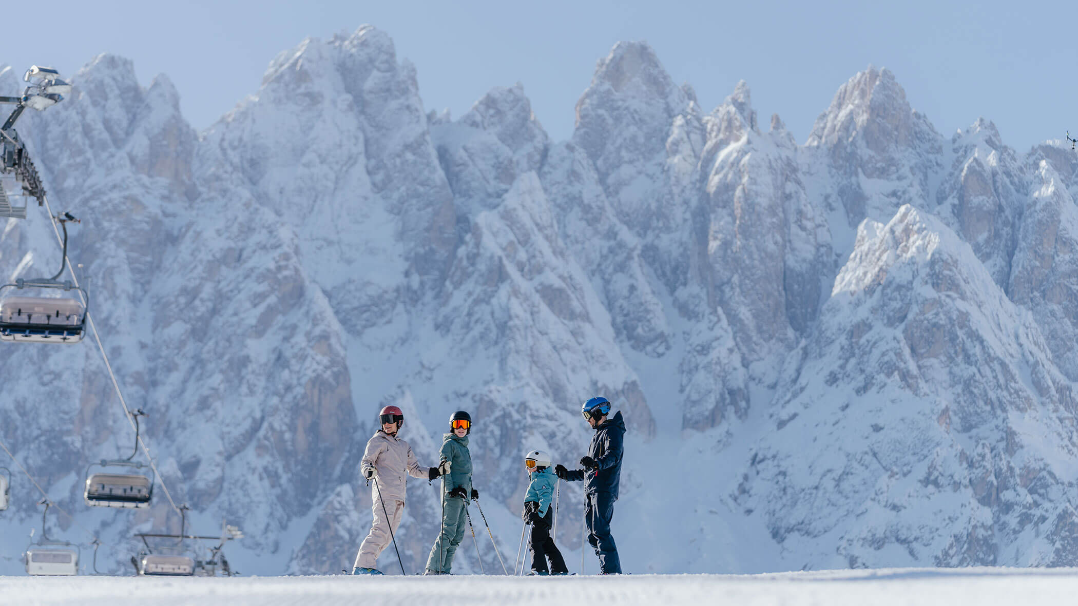 Vier Personen in Skiausrüstung stehen auf verschneitem Boden mit hohen, felsigen, schneebedeckten Bergen im Hintergrund. - Hotel Magdalenahof