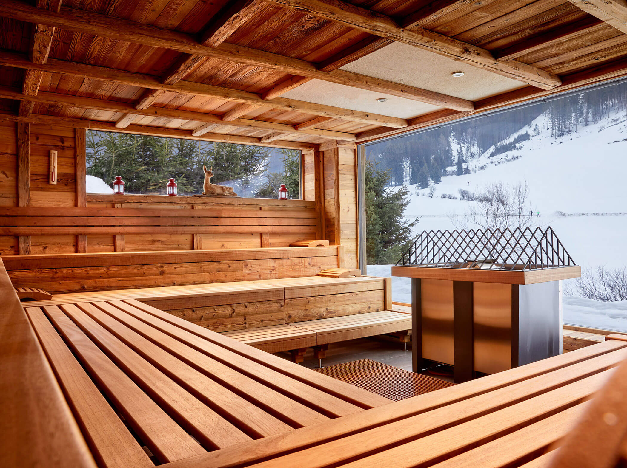 Holzsauna mit großen Fenstern, Blick auf die verschneiten Berge und roten Laternen auf der Fensterbank. - Hotel Magdalenahof