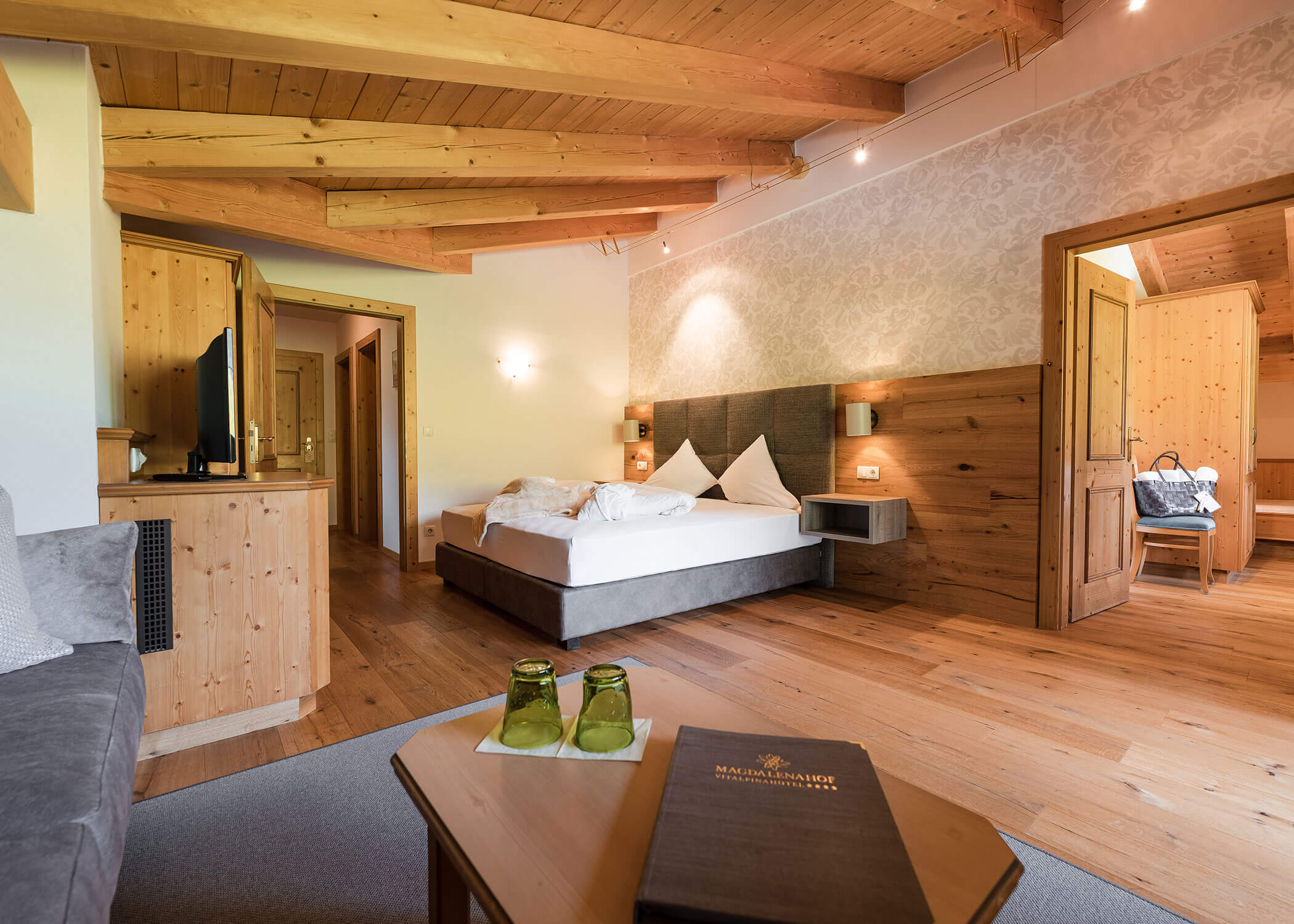 Geräumiges, gemütliches Hotelzimmer mit Holzdekor, Doppelbett, Sofa, TV und Tageslicht. - Hotel Magdalenahof